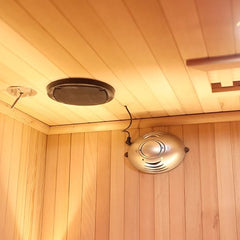 Wooden sauna interior with ceiling lights and a heater.